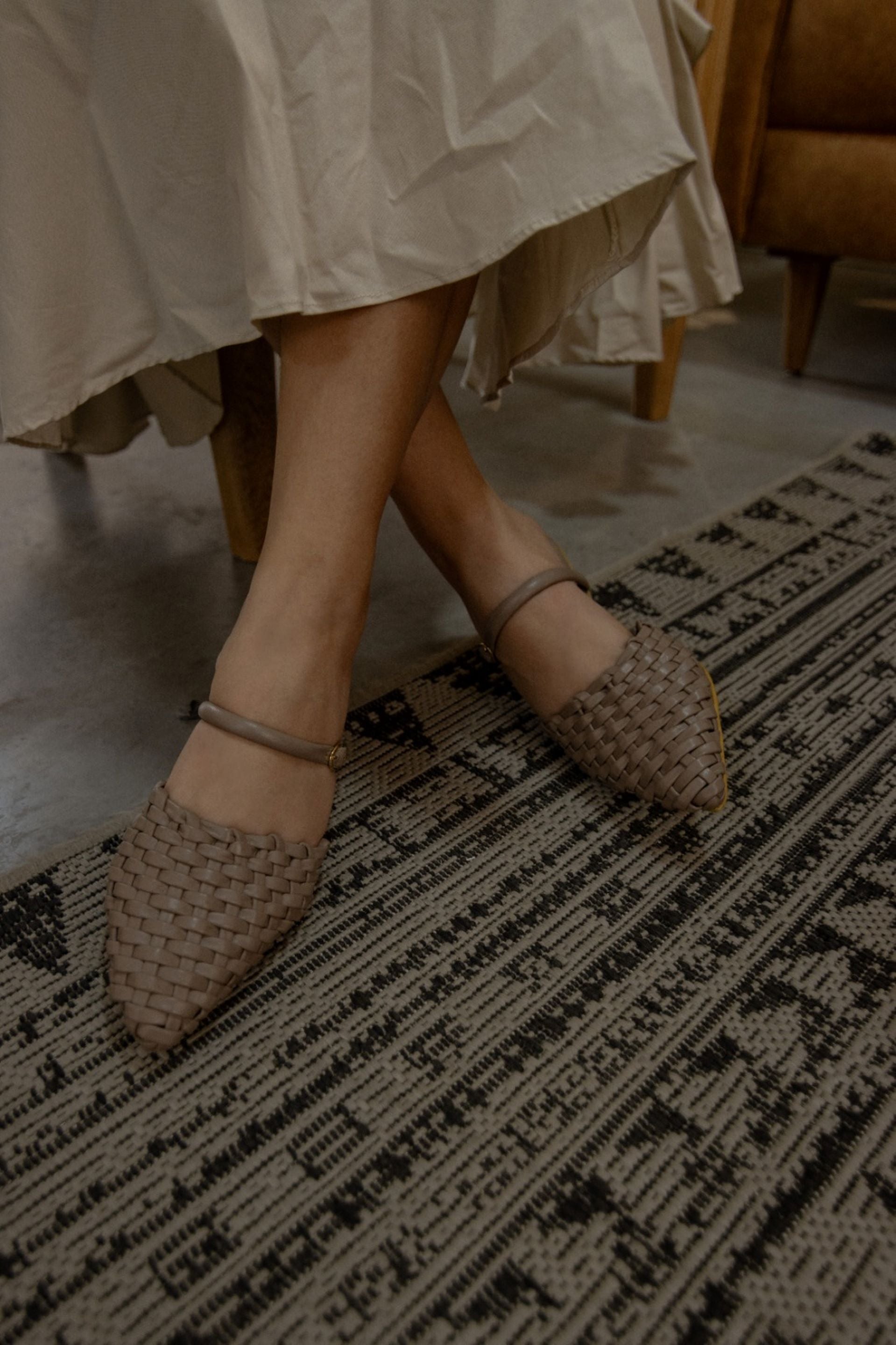 Zapatos tipo mule en tono nude con diseño tejido y correa ajustable en el tobillo con mini tacón forrado de 2.5cm, adelante cerradas en punta, con hebilla, Fabricados en Colombia con cuero de bovino color arena., combinan elegancia y comodidad con un toque artesanal. Perfectos para un look sofisticado y versátil.