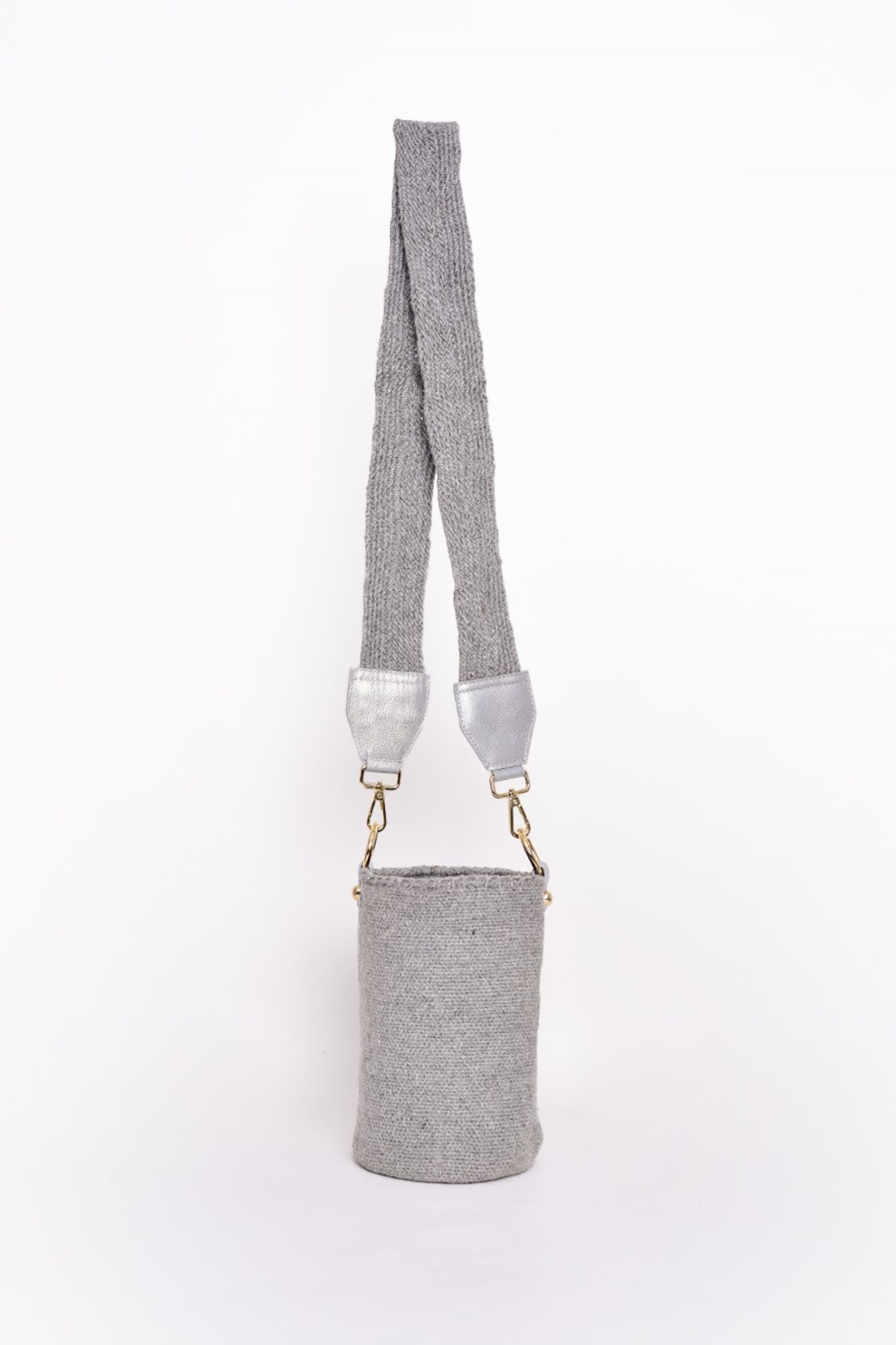 Bolso tipo canasto en tono gris, tejido artesanalmente con lana de alta calidad. Cuenta con una correa ajustable en el mismo material y detalles en cuero con herrajes dorados. Un accesorio elegante y versátil para cualquier ocasión.