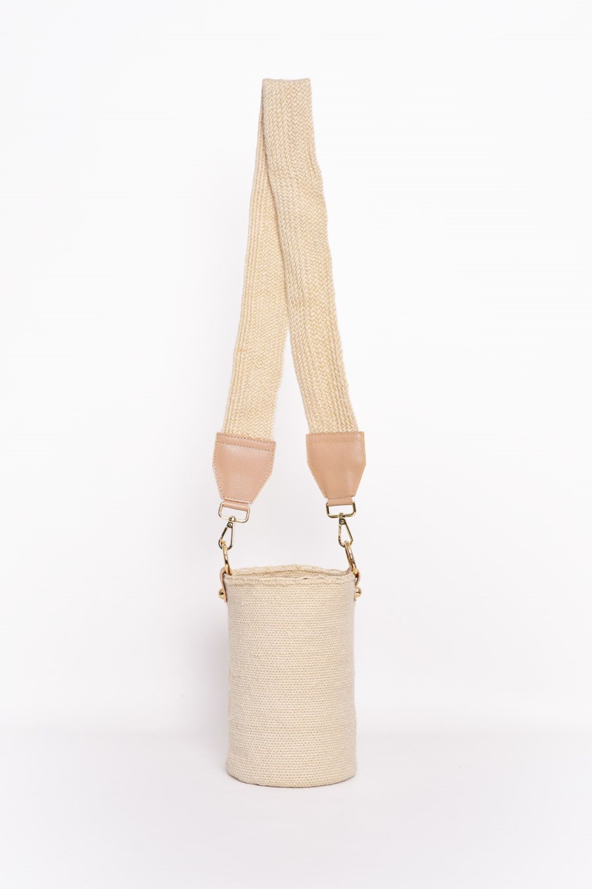 Bolso tipo canasto en tono crudo, tejido artesanalmente con lana de alta calidad. Cuenta con una correa ajustable en el mismo material y detalles en cuero con herrajes dorados. Un accesorio elegante y versátil para cualquier ocasión.