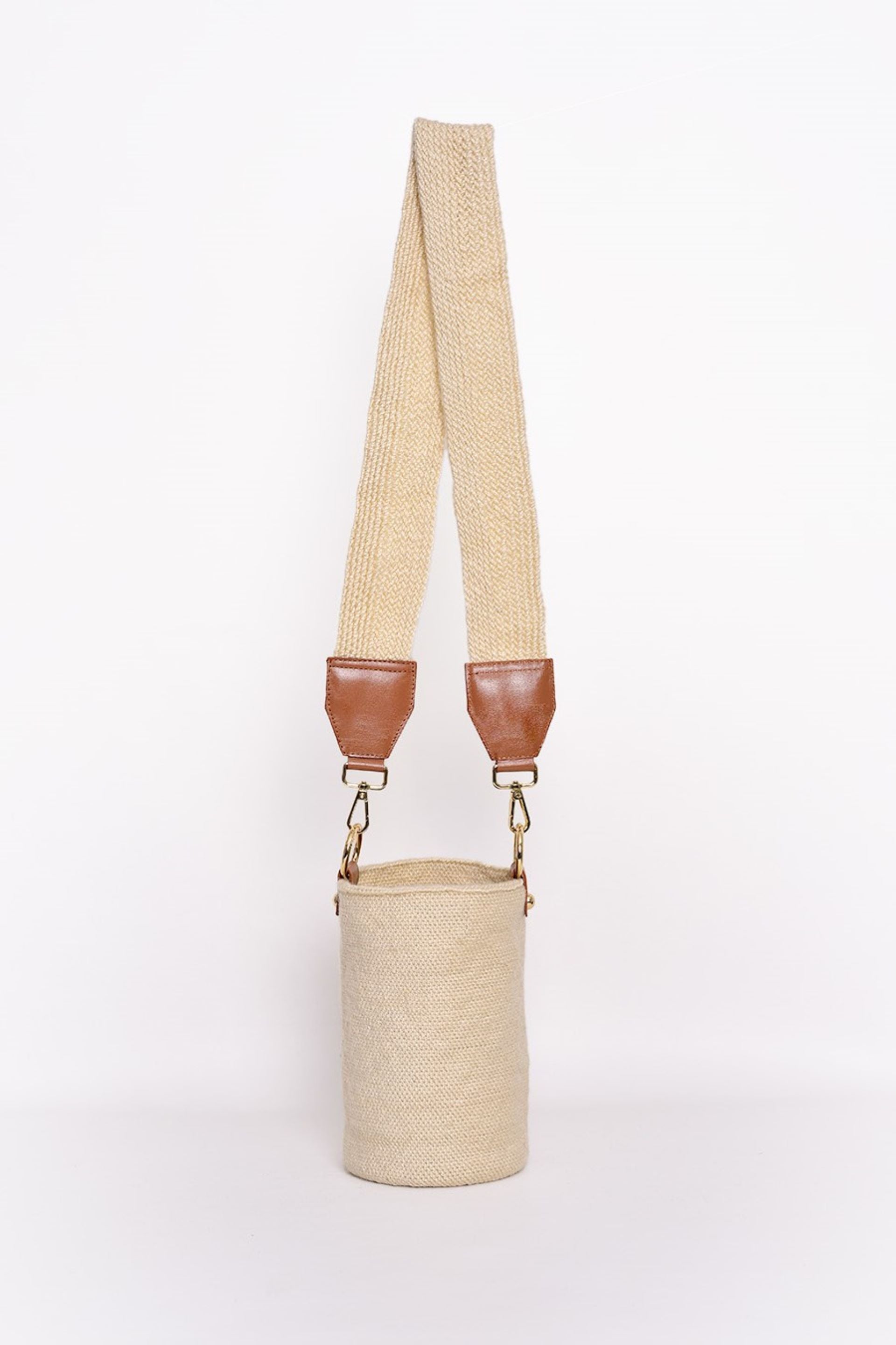 Bolso tipo canasto en tono crudo, tejido artesanalmente con lana de alta calidad. Cuenta con una correa ajustable en el mismo material y detalles en cuero con herrajes dorados. Un accesorio elegante y versátil para cualquier ocasión.