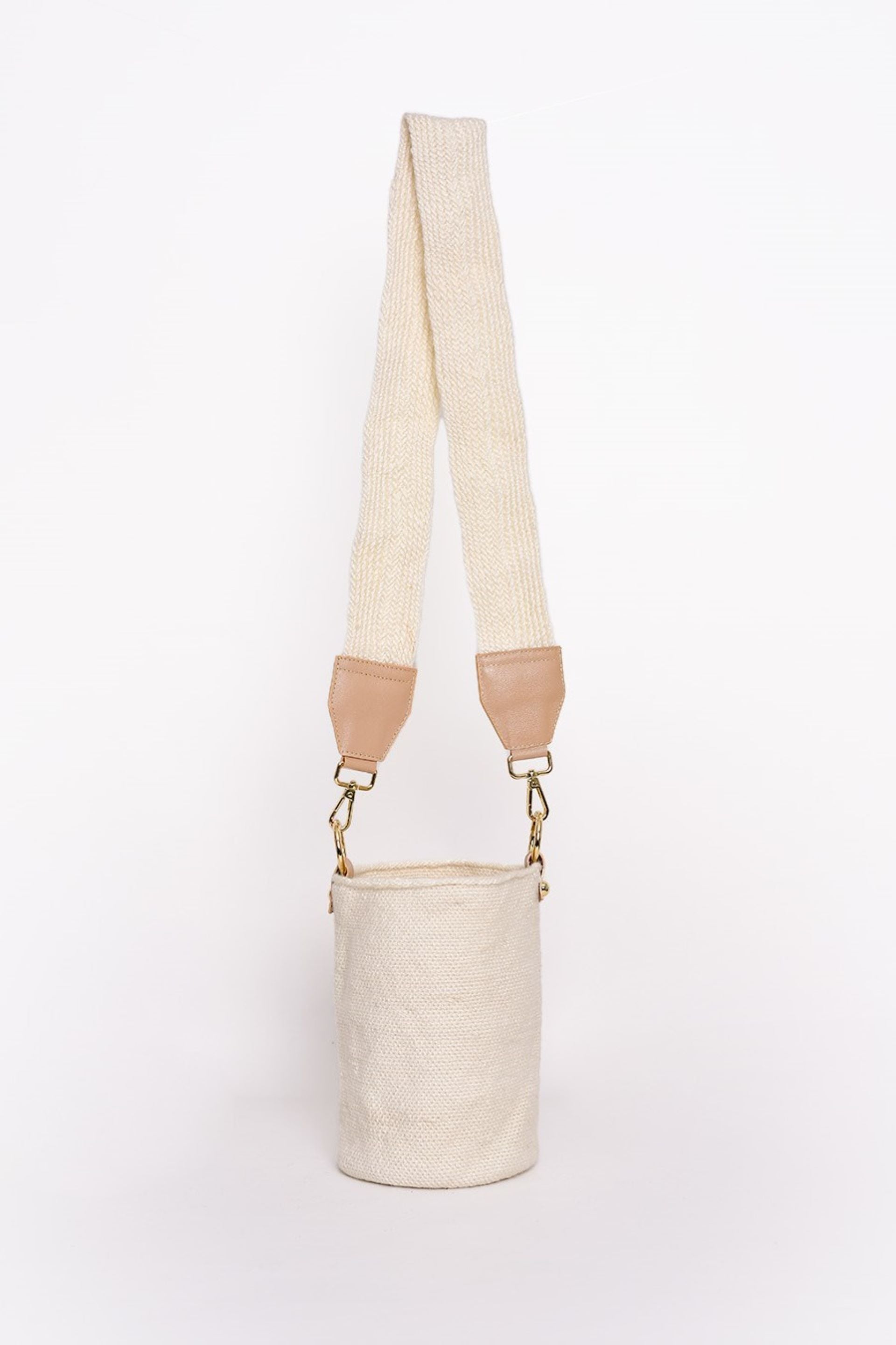 Bolso tipo canasto en tono crudo, tejido artesanalmente con lana de alta calidad. Cuenta con una correa ajustable en el mismo material y detalles en cuero con herrajes dorados. Un accesorio elegante y versátil para cualquier ocasión.