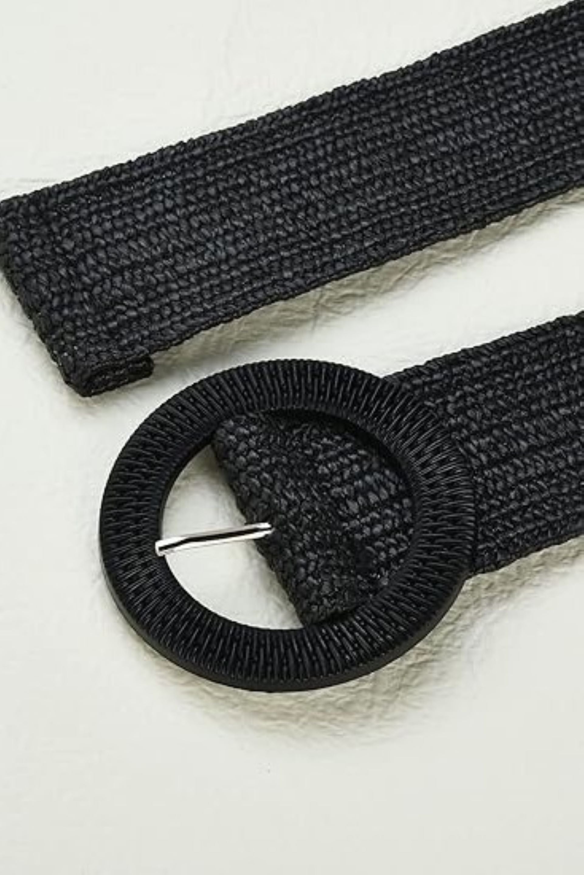 Cinturón negro tejido en fibra natural con hebilla circular y detalle de pasador metálico. Diseño artesanal, elegante y versátil, ideal para complementar cualquier look con un toque sofisticado y moderno.