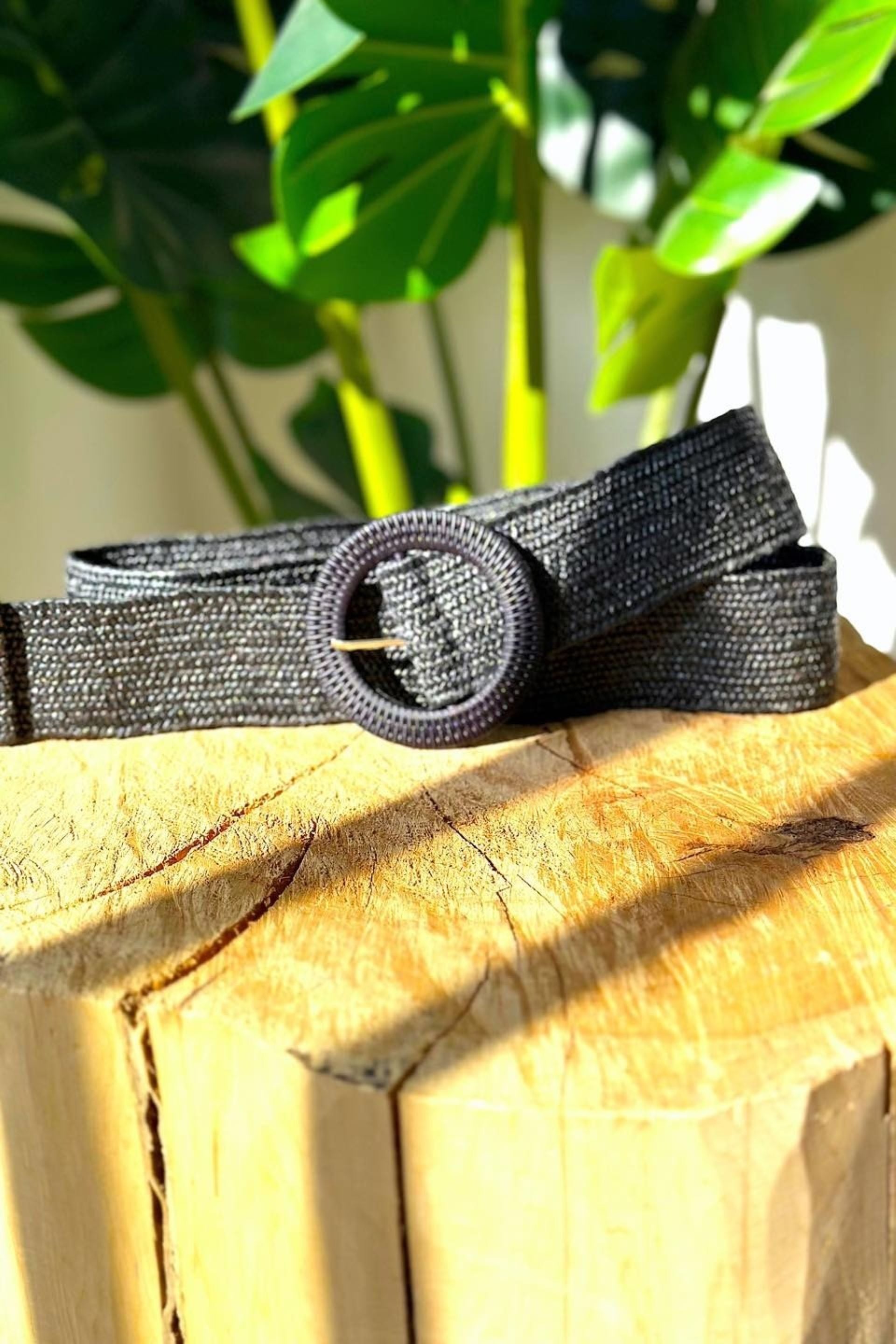 Cinturón negro tejido en fibra natural con hebilla circular y detalle de pasador metálico. Diseño artesanal, elegante y versátil, ideal para complementar cualquier look con un toque sofisticado y moderno.