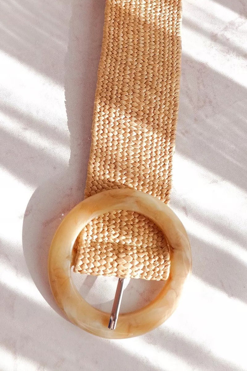 Cinturón tejido en fibra natural con hebilla circular en tonos marrón y beige. Diseño artesanal, versátil y ajustable, ideal para complementar looks casuales o bohemios con un toque elegante y natural.