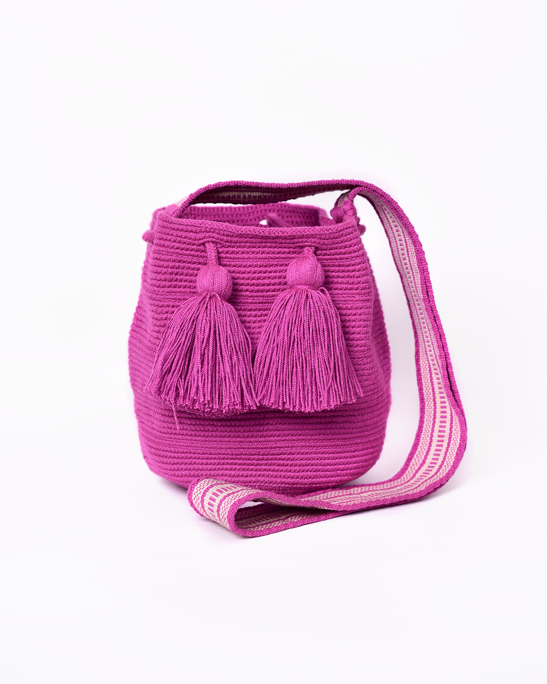 Mochila Wayuu artesanal tejida a mano en color fucsia, con borlas decorativas y asa larga. Diseñada con un patrón tradicional, fabricada por artesanas indígenas de la comunidad Wayuu en Colombia. Ideal para quienes buscan un accesorio único. ¡Compra online en Micerino y luce lo mejor de la moda hecha en Colombia!