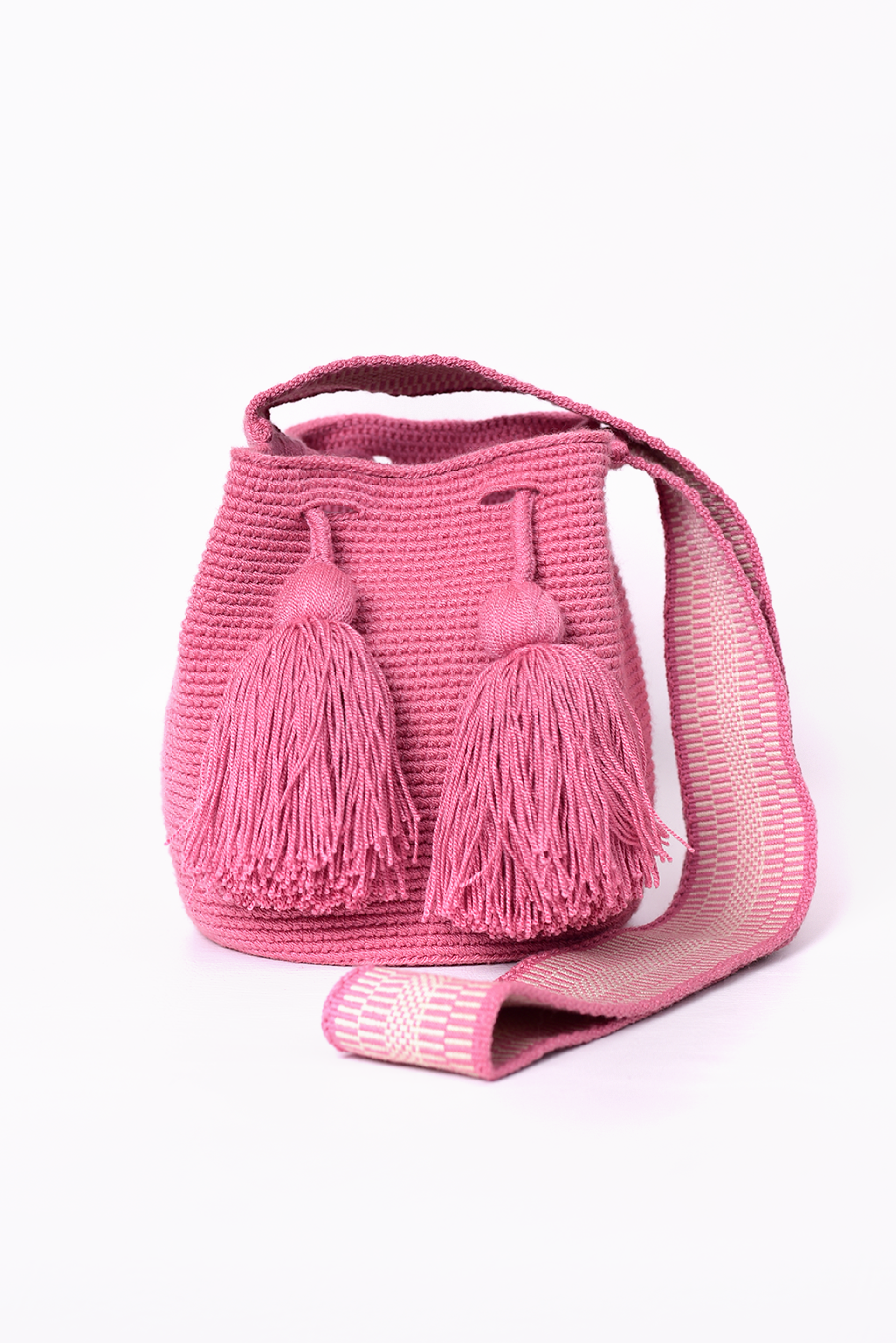 Mochila Wayuu artesanal tejida a mano en color rosa, con borlas decorativas y asa larga. Diseñada con un patrón tradicional, fabricada por artesanas indígenas de la comunidad Wayuu en Colombia. Ideal para quienes buscan un accesorio único. ¡Compra online en Micerino y luce lo mejor de la moda hecha en Colombia!