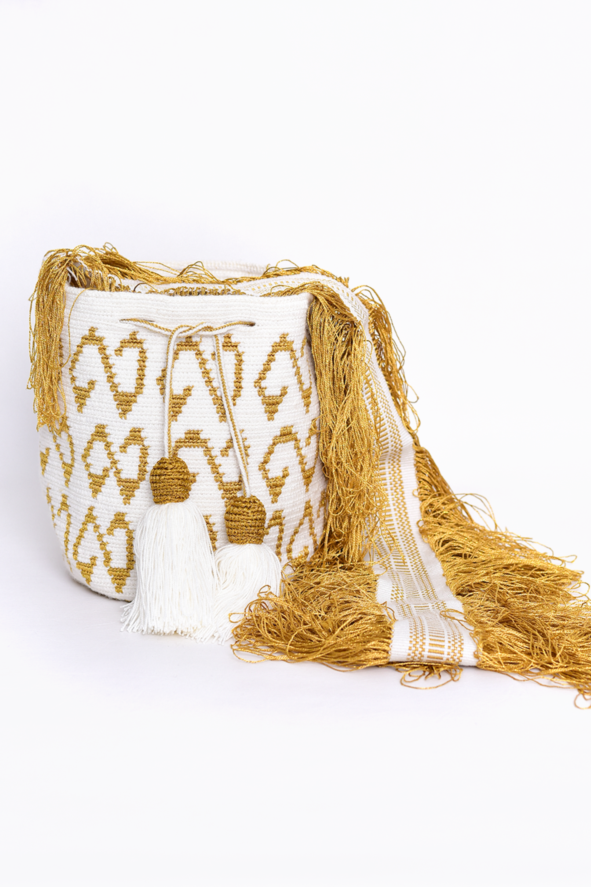 Bolso Wayuu tejido a mano en tonos dorado y blanco, con detalles en borlas y flecos largos. Un diseño artesanal exclusivo que resalta la tradición y el arte de la comunidad Wayuu. Ideal para complementar cualquier look con un toque de autenticidad y elegancia.