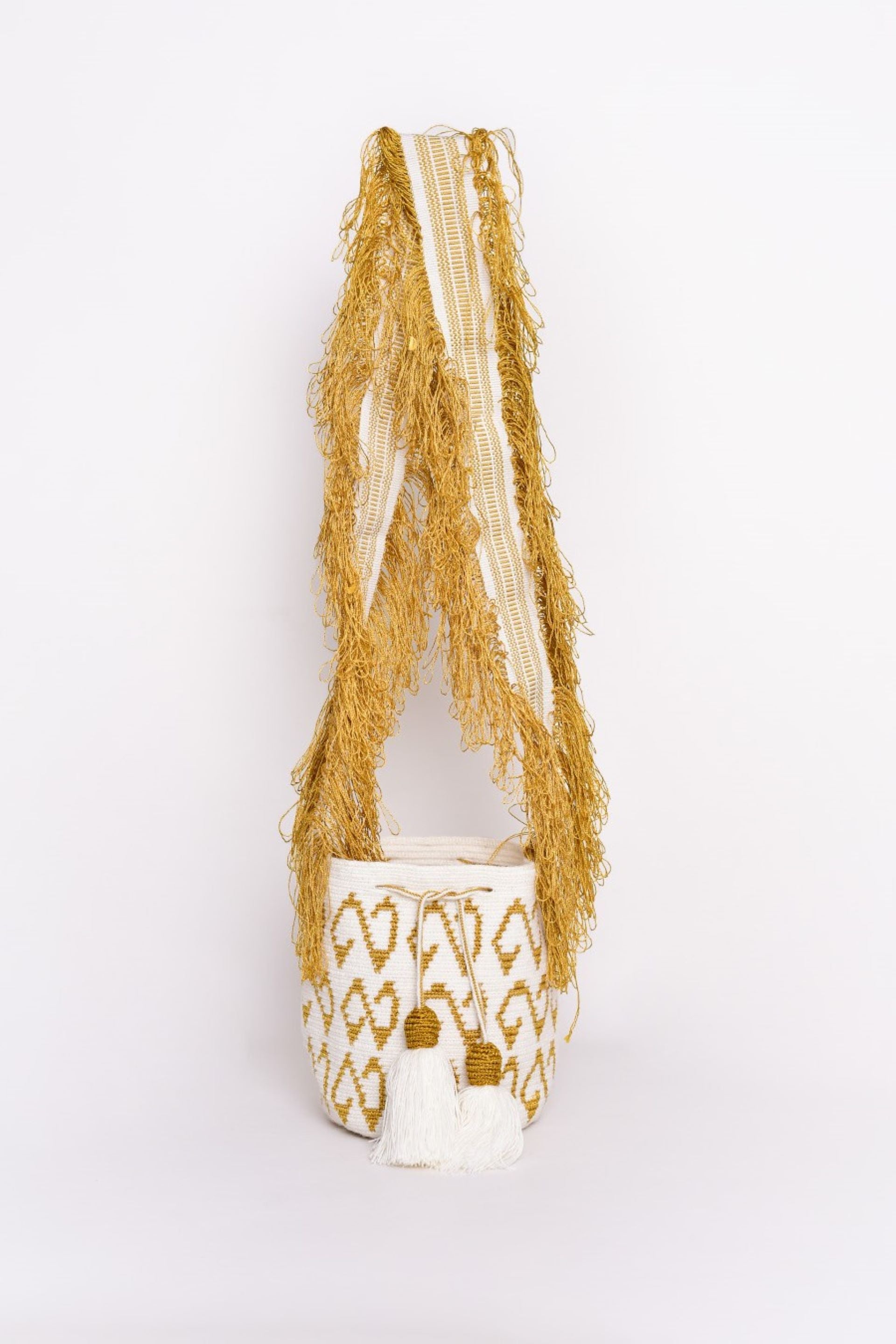 Bolso Wayuu tejido a mano en tonos dorado y blanco, con detalles en borlas y flecos largos. Un diseño artesanal exclusivo que resalta la tradición y el arte de la comunidad Wayuu. Ideal para complementar cualquier look con un toque de autenticidad y elegancia.