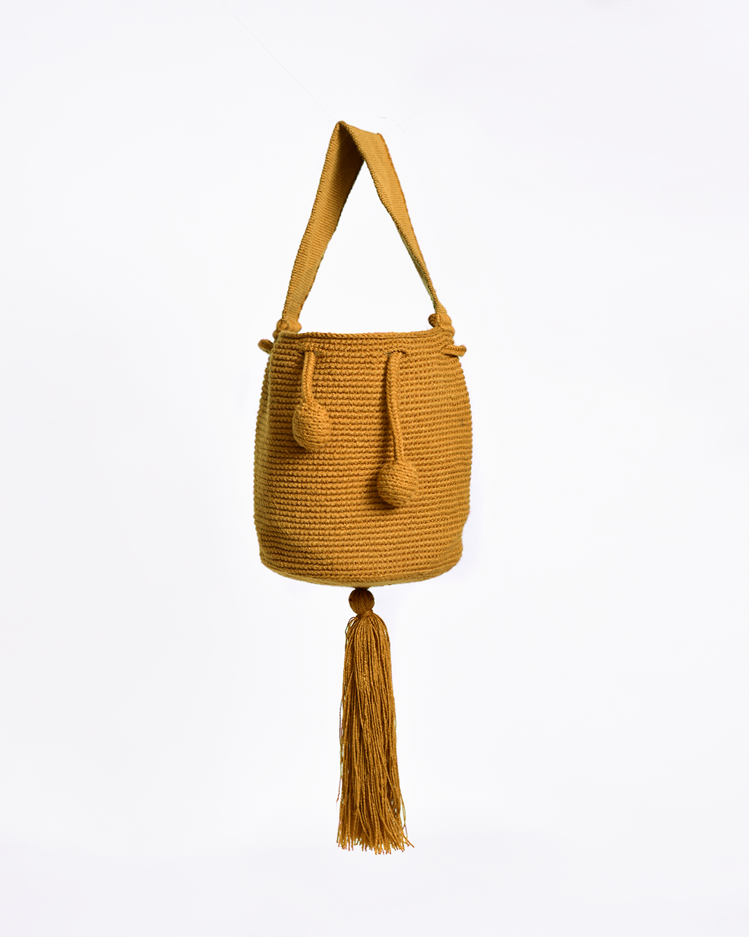 Mini mochila Wayuu artesanal, tejida a mano con hilo unicolor mostaza, con un colgante decorativo. Cuenta con una cargadera corta y un cordón ajustable. Hecha por artesanas de la comunidad Wayuu, reflejando la autenticidad de la moda colombiana.
