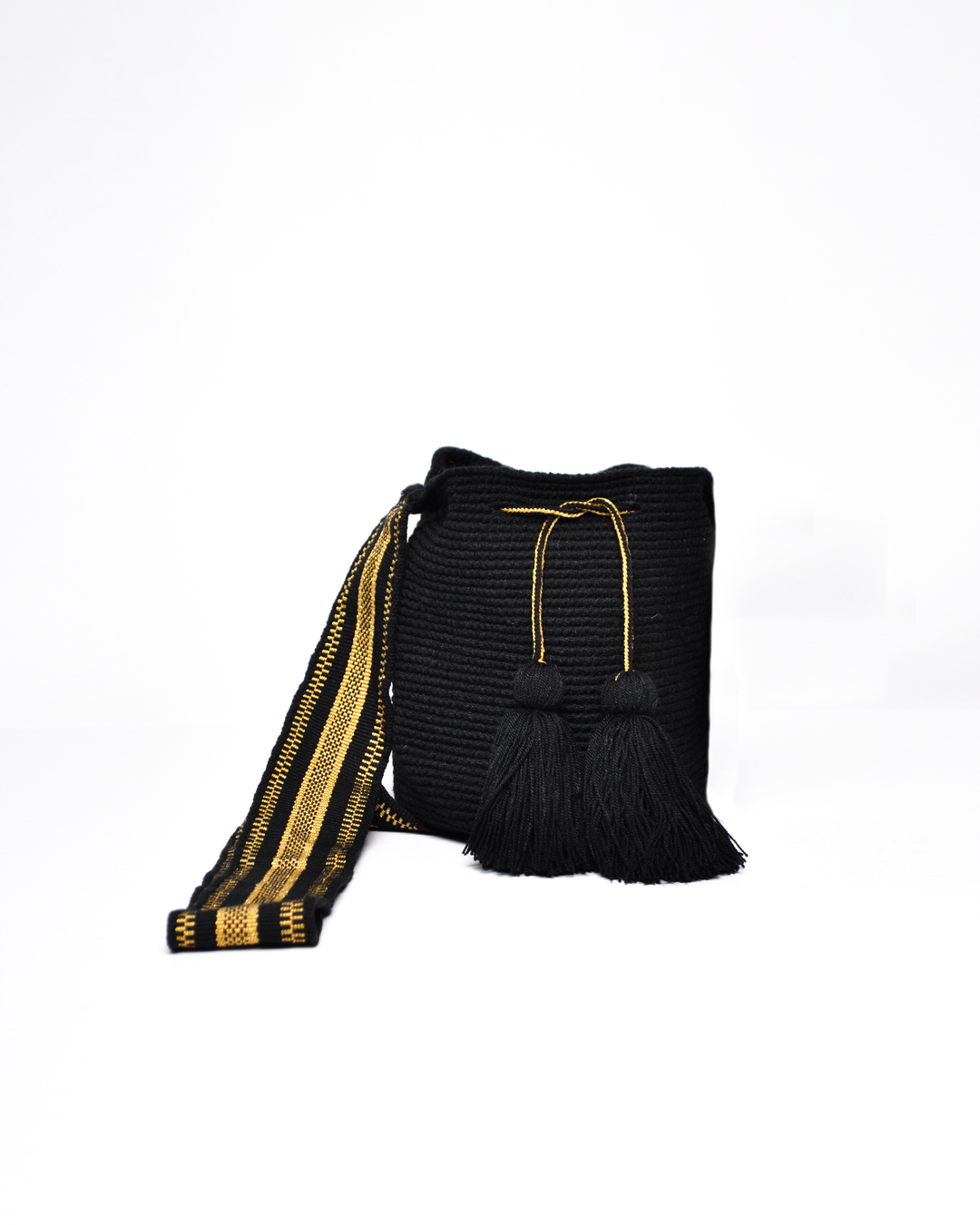 Mochila Wayuu de color negro con detalles en hilo dorado y flecos negros en el cierre. Diseño tradicional con correa ajustable para el hombro.