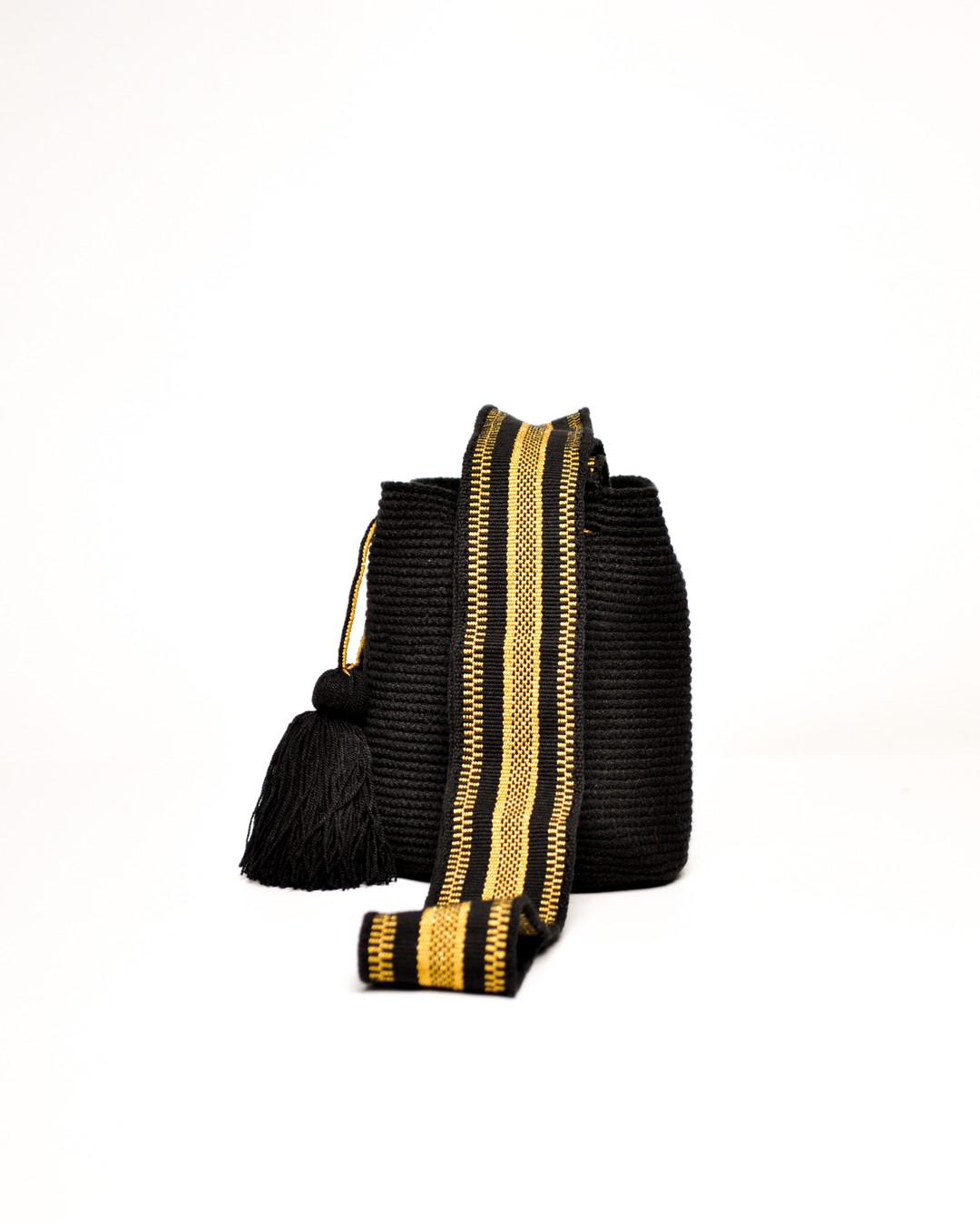 Mochila Wayuu de color negro con detalles en hilo dorado y flecos negros en el cierre. Diseño tradicional con correa ajustable para el hombro.