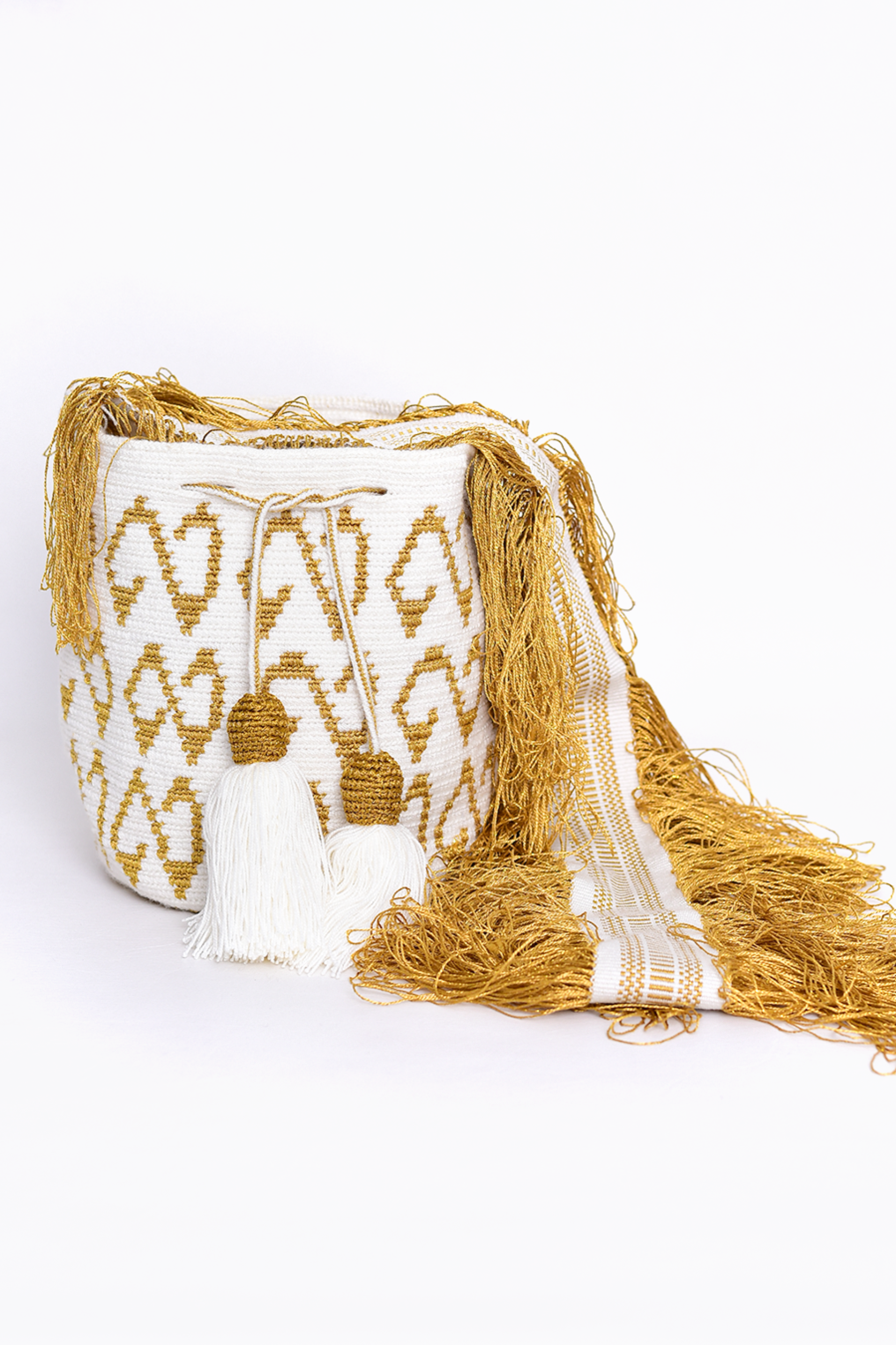 Bolso Wayuu tejido a mano en tonos dorado y blanco, con detalles en borlas y flecos largos. Un diseño artesanal exclusivo que resalta la tradición y el arte de la comunidad Wayuu. Ideal para complementar cualquier look con un toque de autenticidad y elegancia.
