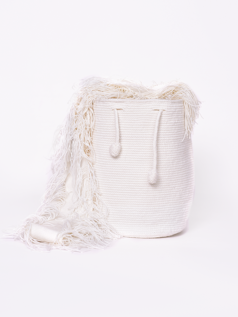 Mochila blanca, de cargadera larga de flecos tejida unicolor, cordón ajustable.